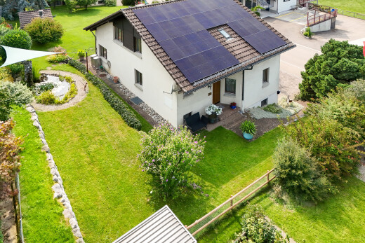außenansicht mit drone view, rasen, solaranlage, stuckverkleidung, und zaun