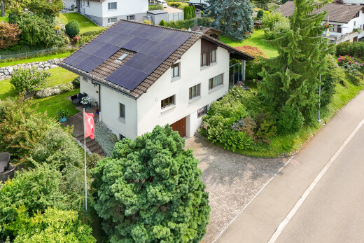 außenansicht mit solaranlage, drone view, stuckverkleidung, eingebaute garage, und auffahrt