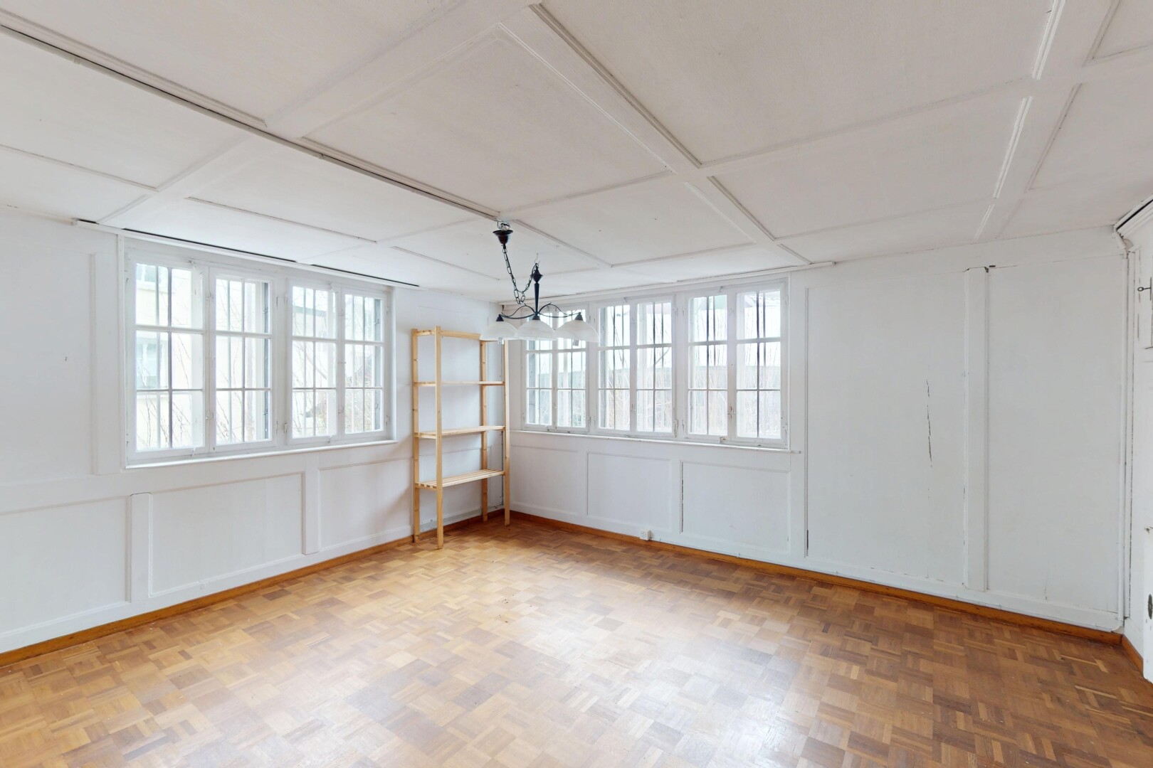 pièce vide avec lumière naturelle, plafond suspendu, lustre remarquable, et mur panneauté