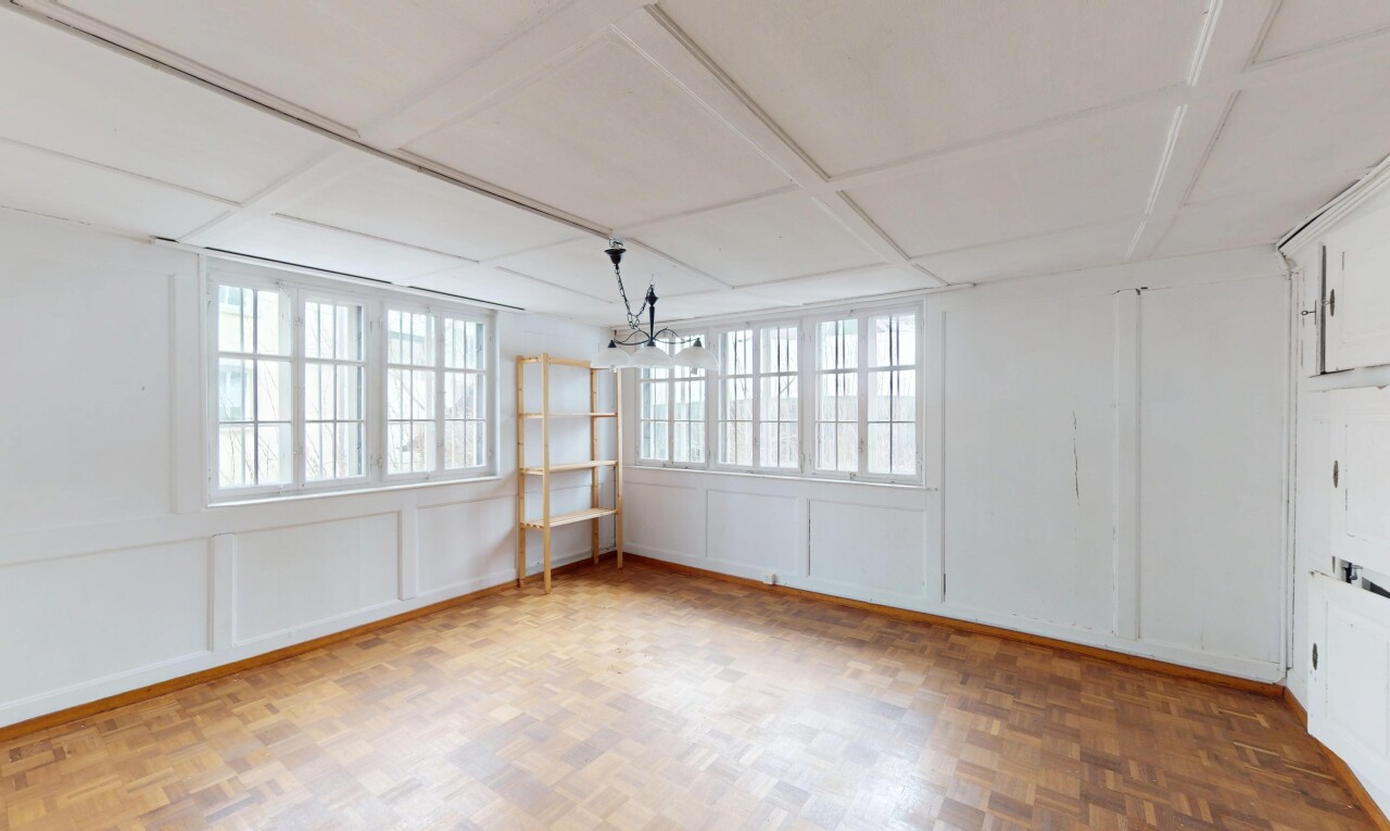 pièce vide avec lumière naturelle, plafond suspendu, lustre remarquable, et mur panneauté
