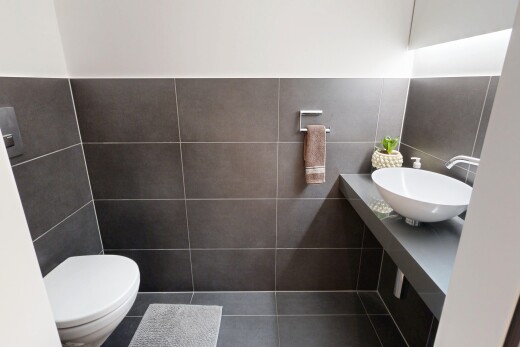 salle de bains avec toilette, lavabo (ou coiffeuse selon le contexte), tile wall, mur en carrelage, et inside property