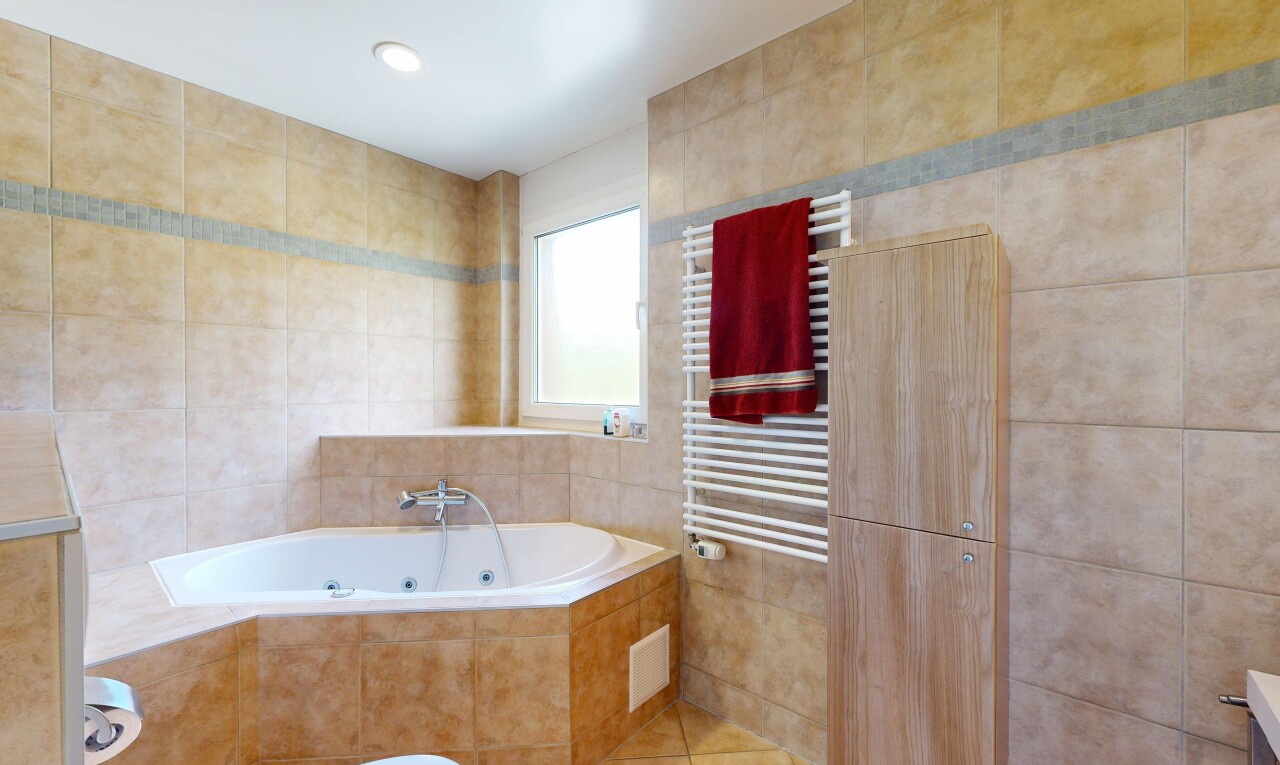 salle de bains avec chauffe-serviettes, tile wall, mur en carrelage, radiateur, et bain