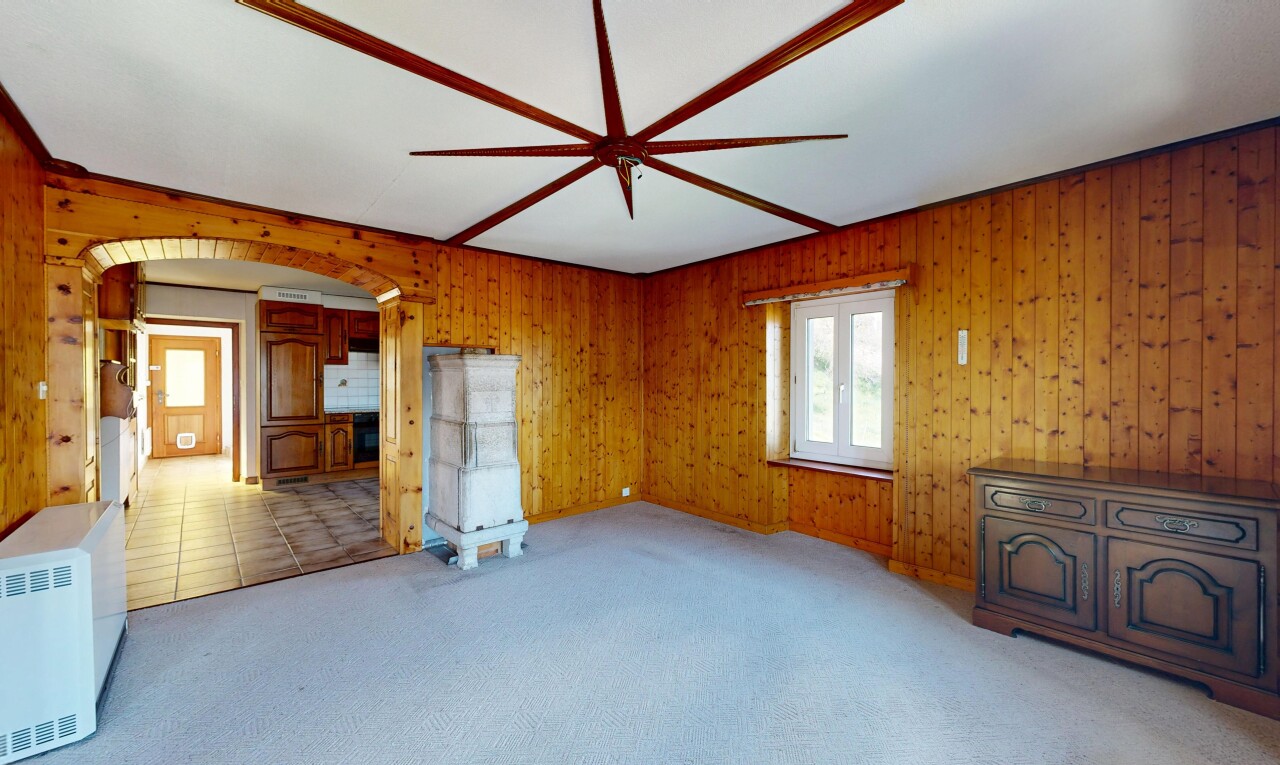 spare room featuring light carpet, arched walkways, wood walls, and a ceiling fan