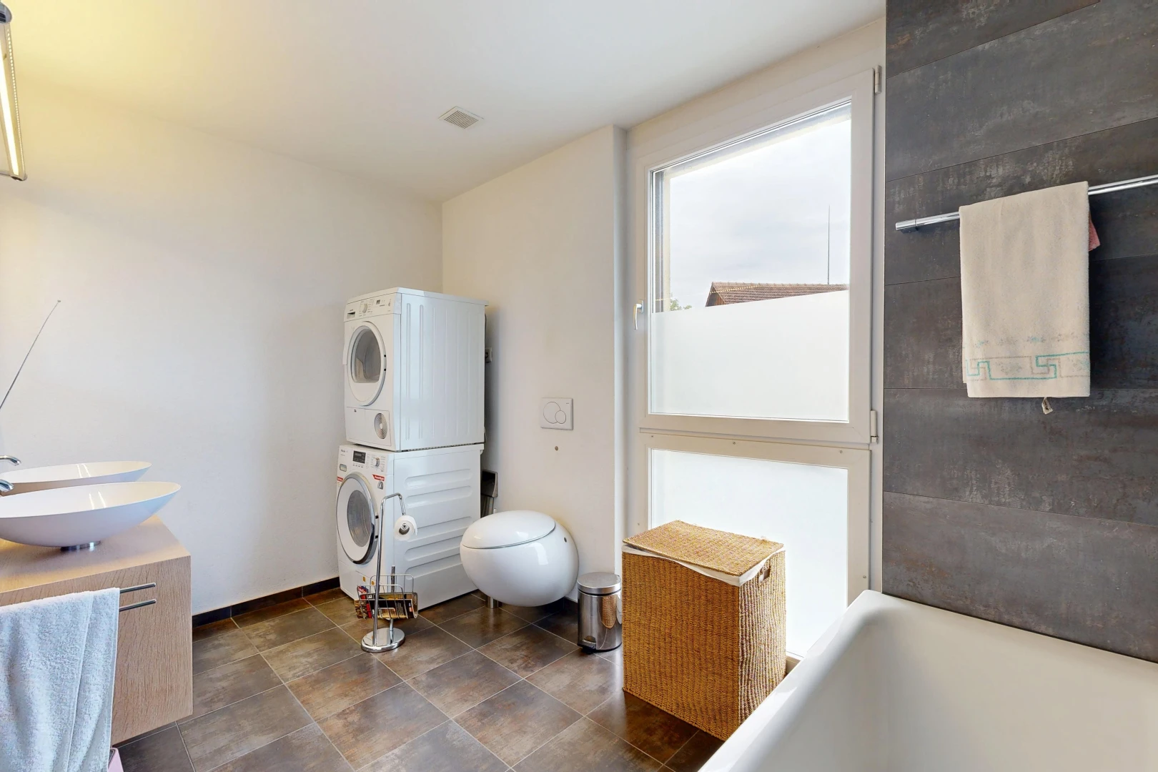 full bath featuring a tub to relax in, stacked washer / dryer, and vanity