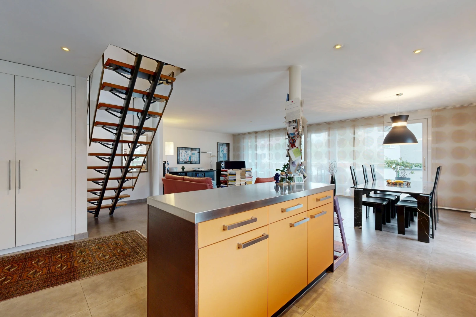 kitchen featuring stainless steel counters, a kitchen island, open floor plan, hanging light fixtures, and modern cabinets