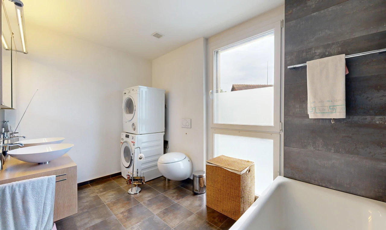 full bath featuring a tub to relax in, stacked washer / dryer, and vanity