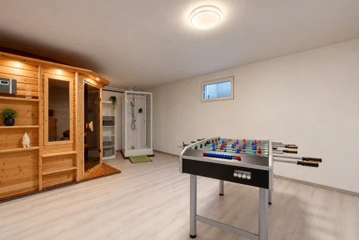 salon avec cloison sèche, drywall, sous-sol, sauna, et sol en finition bois