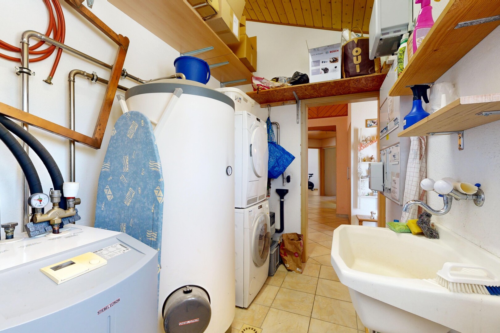 salle de bains avec inside property, évier, lave-linge et sèche-linge superposés, sol en carrelage, et tile floor