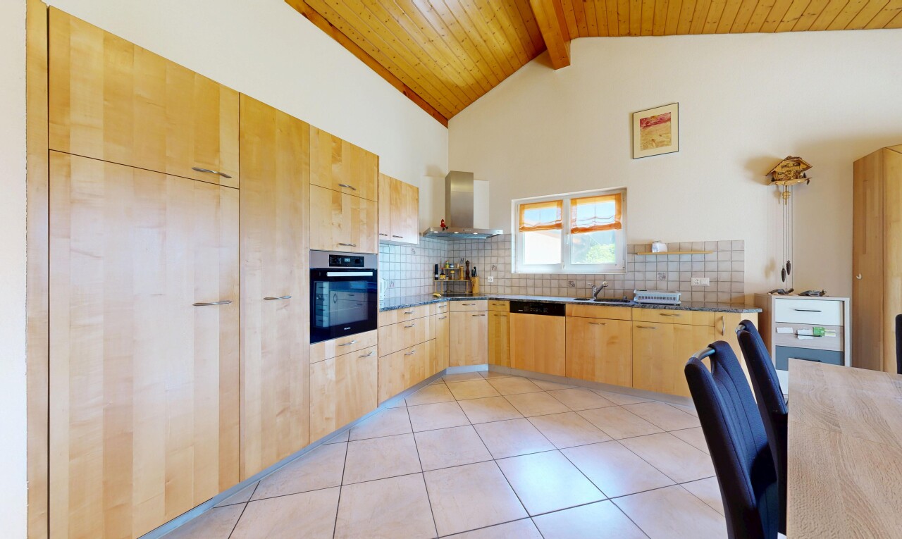 cuisine avec armoires marron clair, light brown cabinets, plans de travail, dark countertops, et four