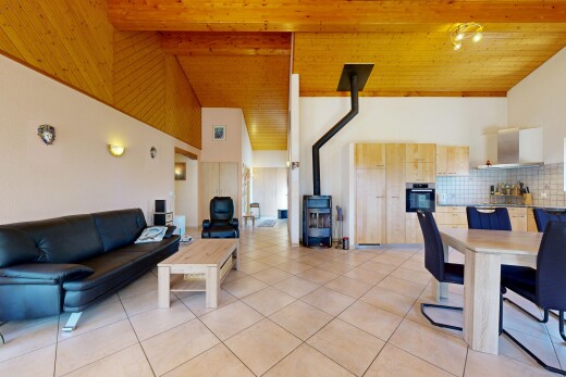living / dining area featuring a high wooden beamed ceiling, a wood stove, and light tile patterned floors