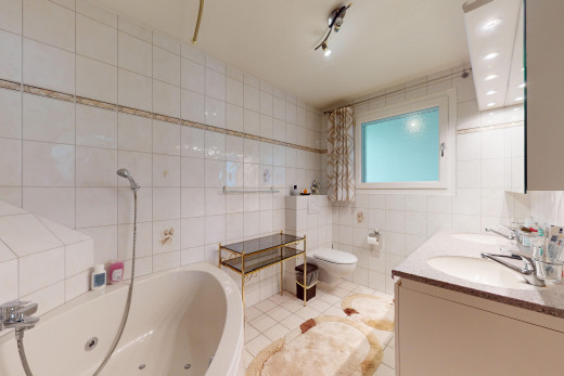 salle de bains avec mur carrelé, vasque, lumière naturelle, et toilettes