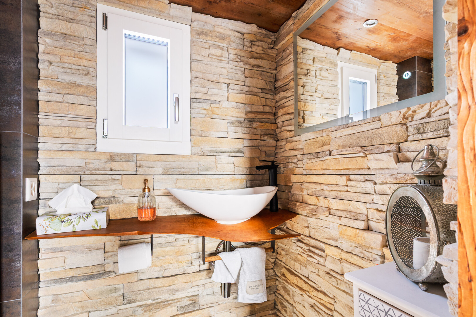 salle de bains avec mur en pierre, stone wall, lavabo (ou coiffeuse selon le contexte), inside property, et évier