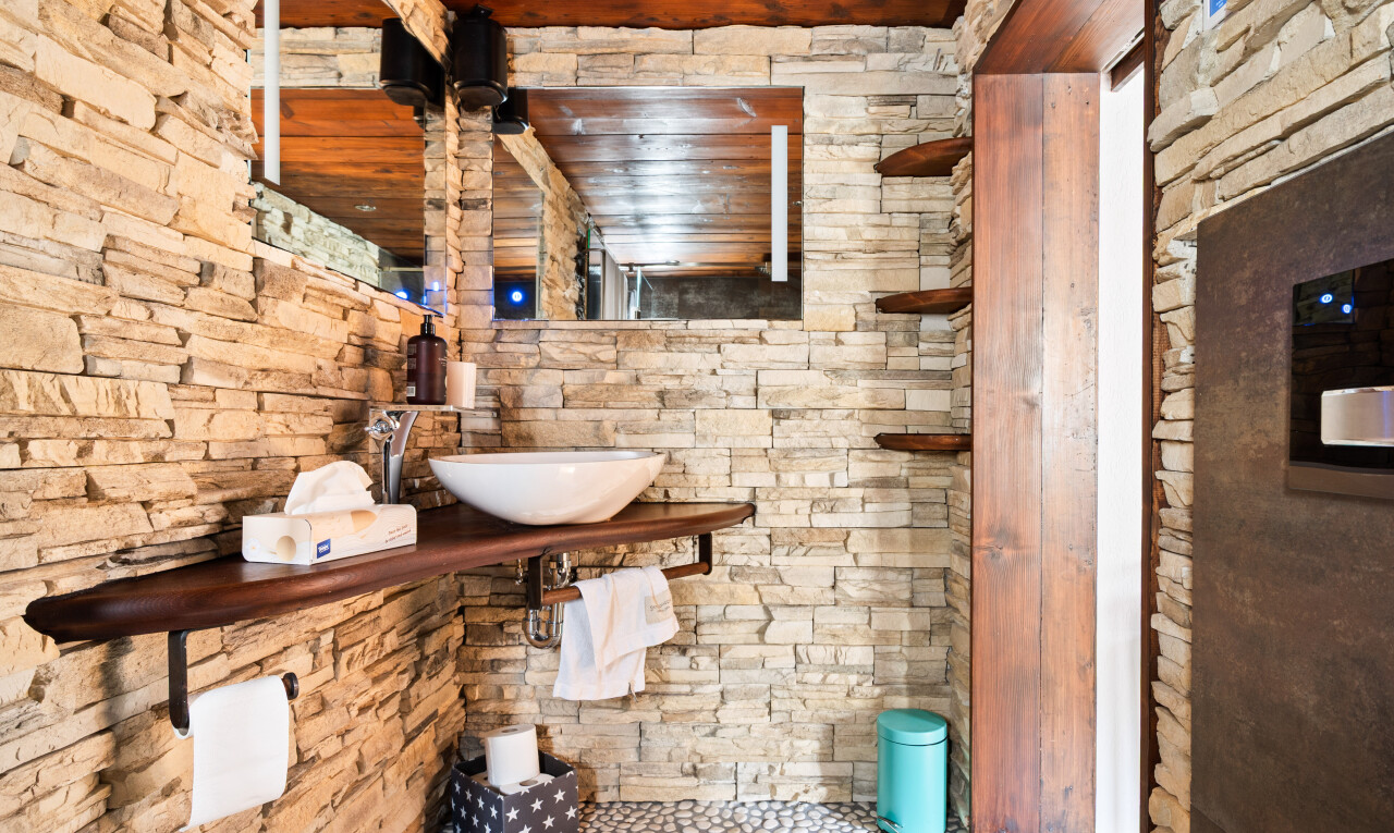 salle de bains avec mur en pierre, stone wall, miroir, inside property, et évier