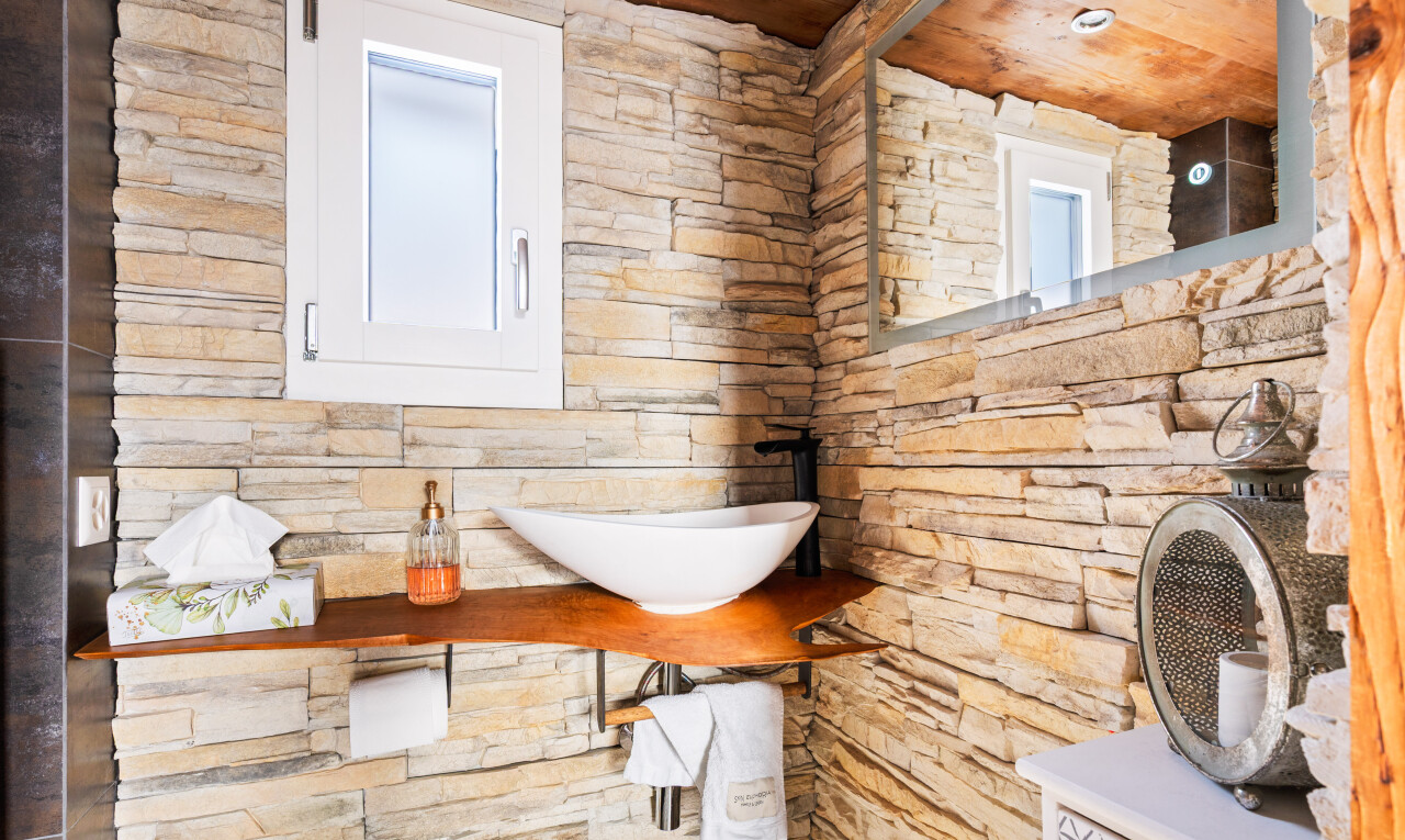salle de bains avec mur en pierre, stone wall, lavabo (ou coiffeuse selon le contexte), inside property, et évier