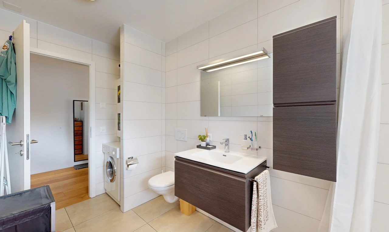 salle de bains avec lavabo (ou coiffeuse selon le contexte), miroir, tile wall, mur en carrelage, et light floor