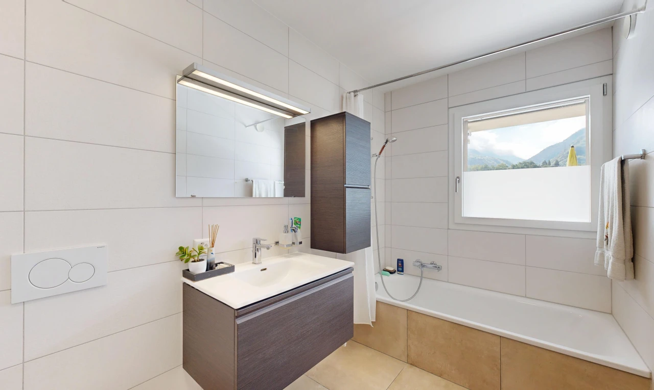 salle de bains avec lavabo (ou coiffeuse selon le contexte), douche-bain combinés, salle de bain complète, miroir, et évier