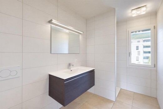 salle de bains avec mur en carrelage, tile wall, lavabo (ou coiffeuse selon le contexte), miroir, et sol en carrelage