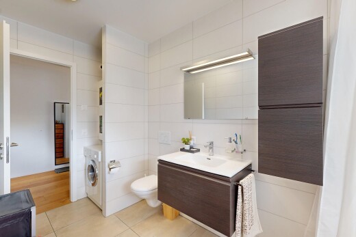 salle de bains avec lavabo (ou coiffeuse selon le contexte), miroir, tile wall, mur en carrelage, et light floor