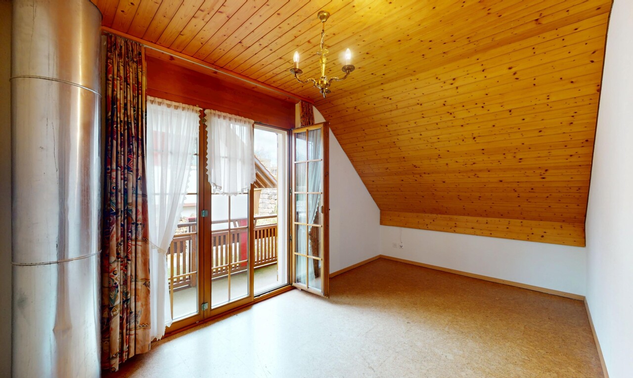 leerer raum mit gipskartonwand, dachschräge, natürliches licht, holzdecke, und bemerkenswerter kronleuchter