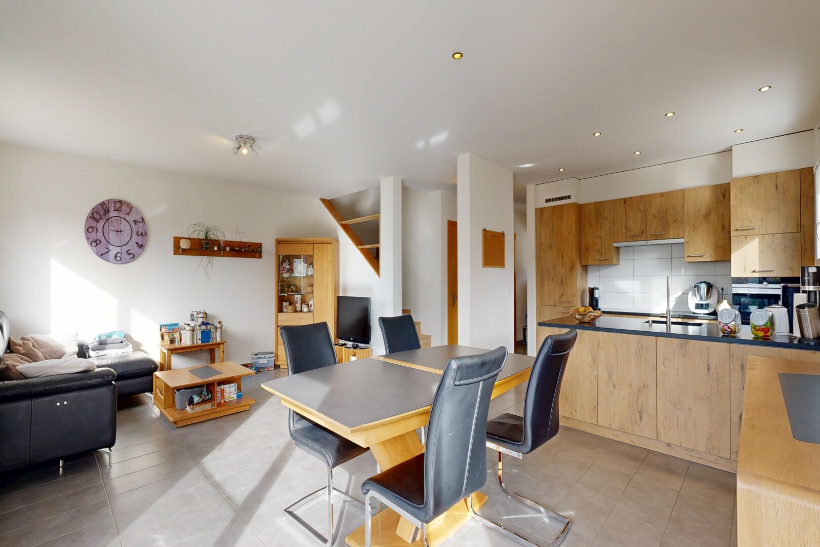 kitchen featuring open floor plan, decorative backsplash, light wood finish cabinets, a peninsula, and dark countertops