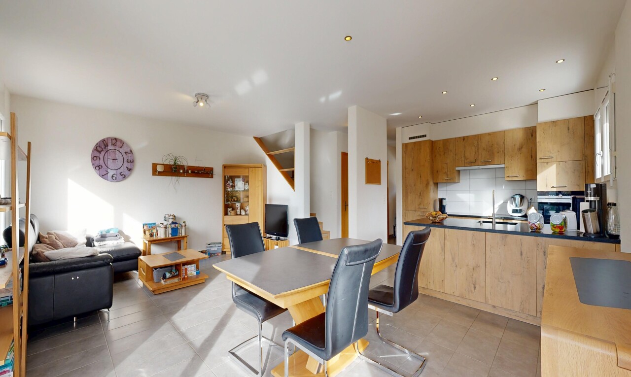 kitchen featuring open floor plan, decorative backsplash, light wood finish cabinets, a peninsula, and dark countertops