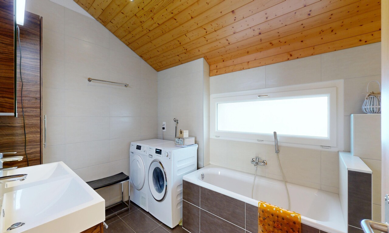 laundry room featuring tile walls, dark tile patterned floors, vaulted ceiling, and washing machine and clothes dryer