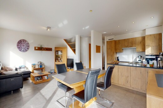 kitchen featuring open floor plan, decorative backsplash, light wood finish cabinets, a peninsula, and dark countertops
