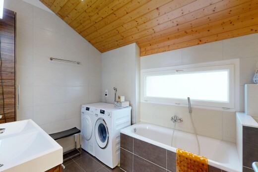 laundry room featuring tile walls, dark tile patterned floors, vaulted ceiling, and washing machine and clothes dryer