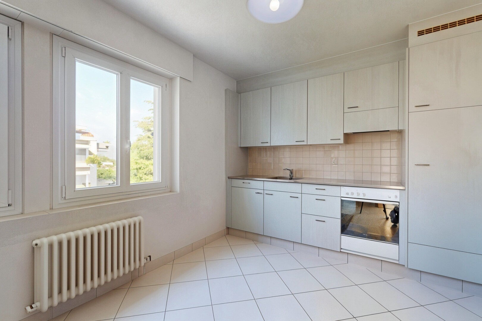 cuisine avec radiateur, four, natural light, lumière naturelle, et évier