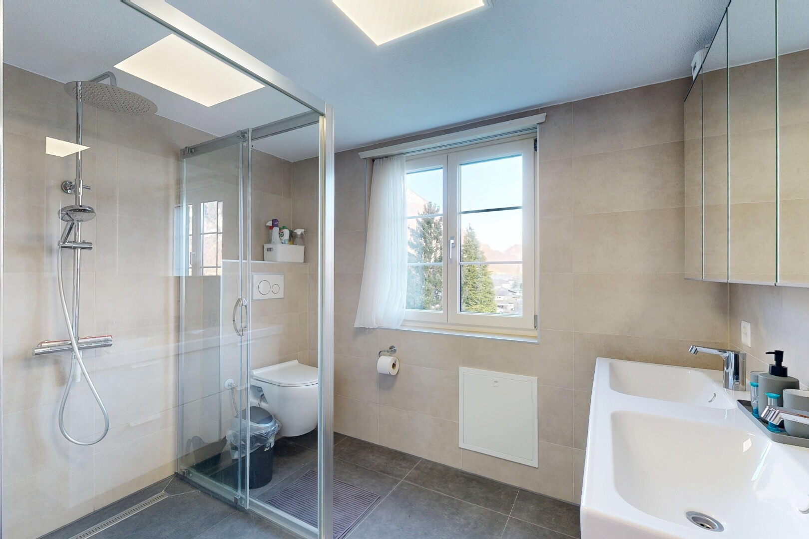 bathroom with a stall shower, double vanity, tile walls, and plenty of natural light