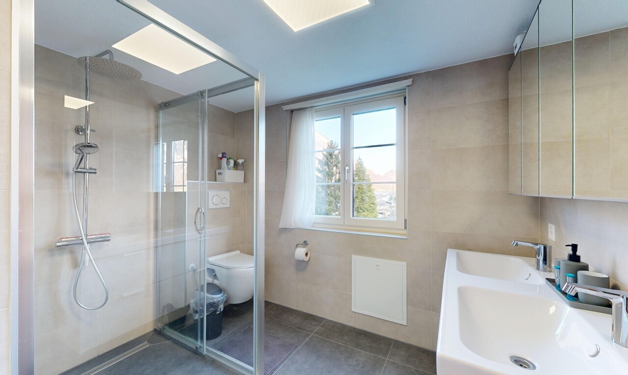 bathroom with a stall shower, double vanity, tile walls, and plenty of natural light