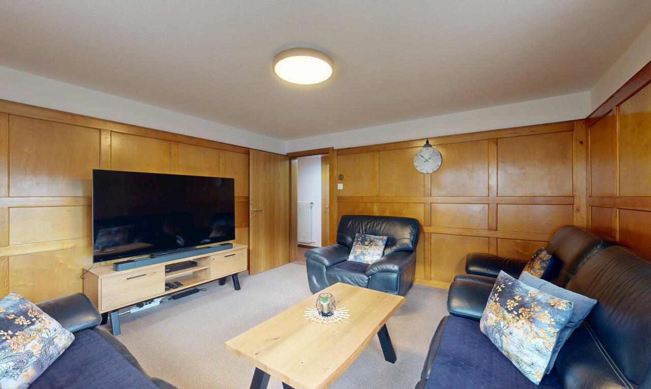 living area with a decorative wall, light carpet, and wood walls