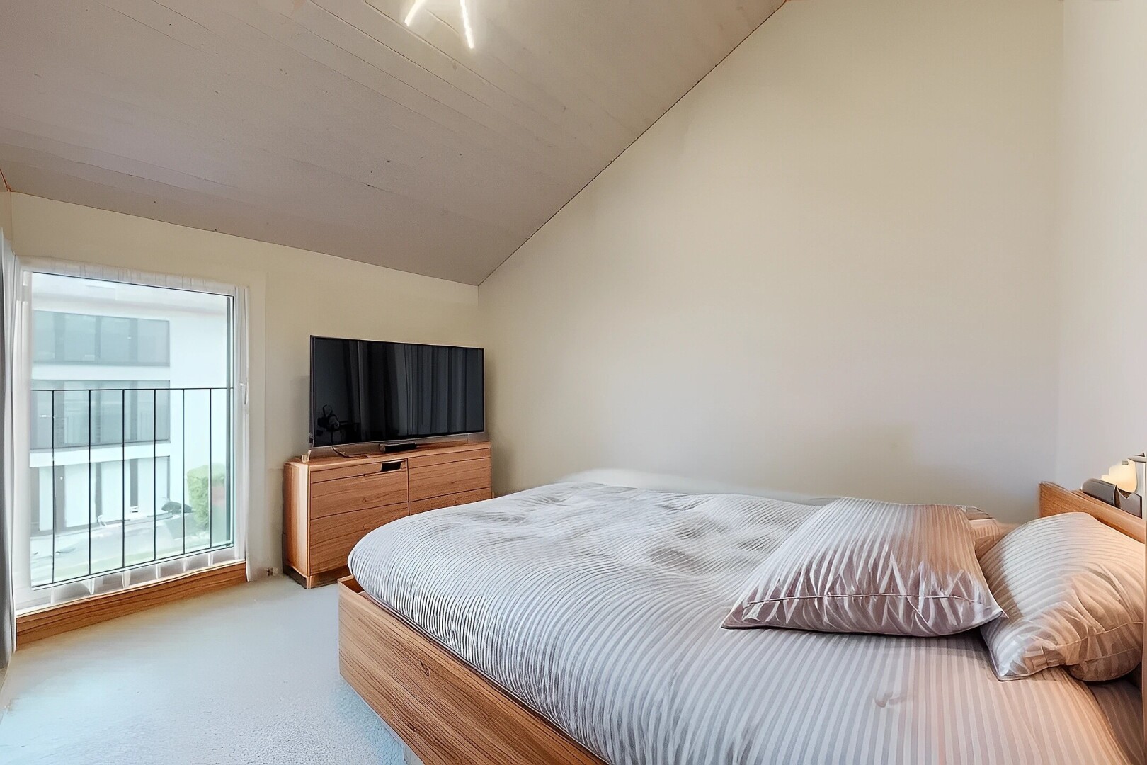 chambre avec cloison sèche, télévision, plafond voûté, lumière naturelle, et moquette