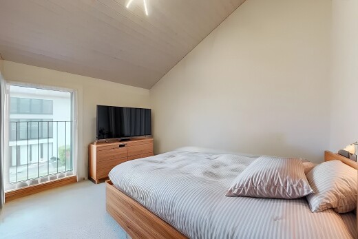 zimmer / schlafzimmer mit natürliches licht, fernseher, teppich, gipskartonwand, und dachschräge