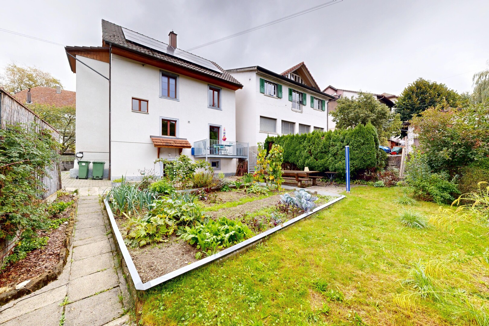 façade avec bardage en stuc, panneaux solaires, pelouse, overcast, et jardin