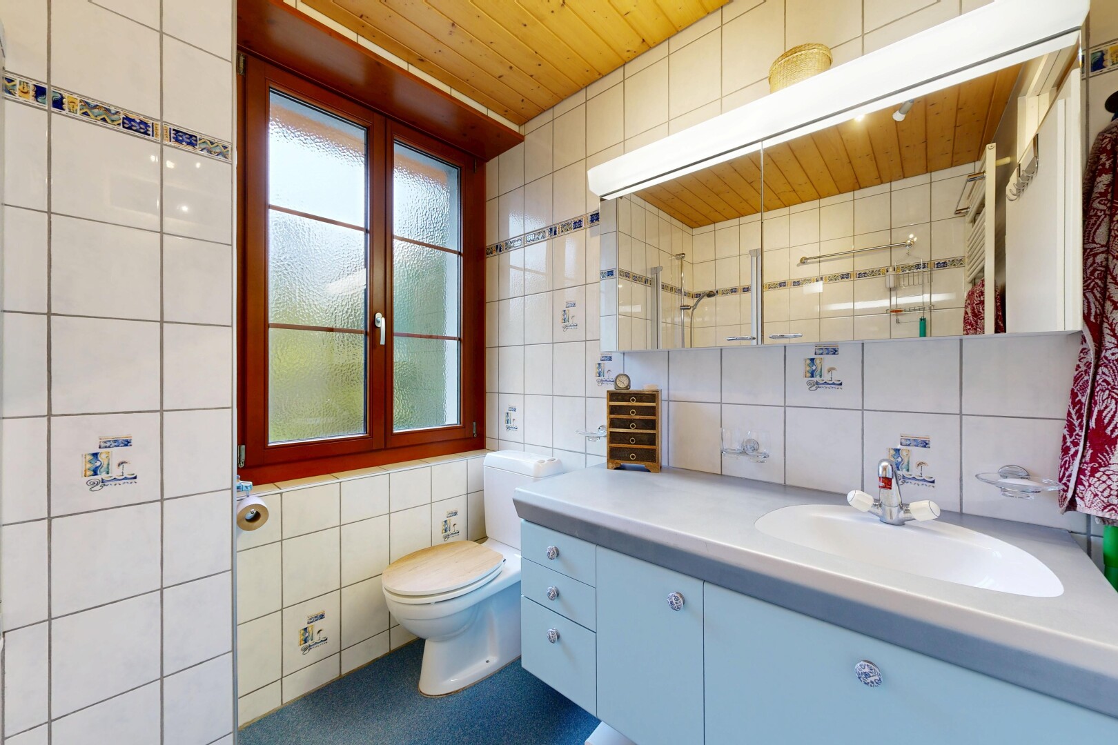 salle de bains avec tile wall, mur en carrelage, miroir, lavabo (ou coiffeuse selon le contexte), et inside property