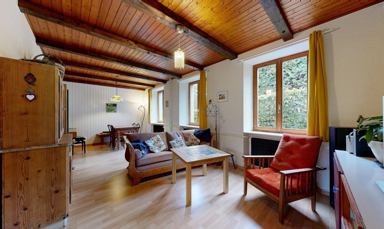salon avec sol en finition bois, wood finish floor, inside property, plafond à poutres, et beamed ceiling