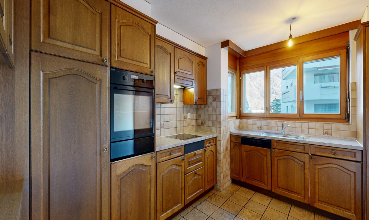 cuisine avec armoires en arc, arched cabinets, armoires marron moyen, medium brown cabinets, et light countertops