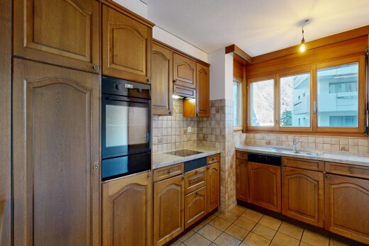 cuisine avec armoires en arc, arched cabinets, armoires marron moyen, medium brown cabinets, et light countertops