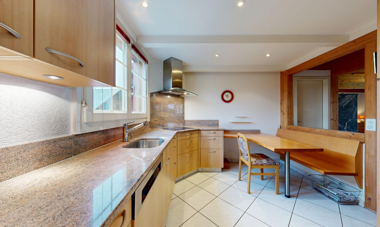 cuisine avec hotte, armoires marron clair, inside property, plans de travail en pierre, et lave-vaisselle