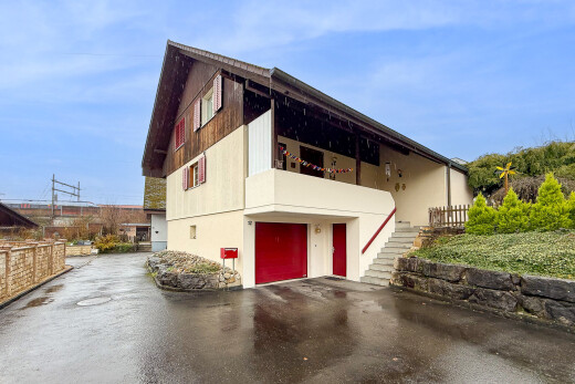 façade avec garage intégré, property visible, balcon, bardage vertical, et allée