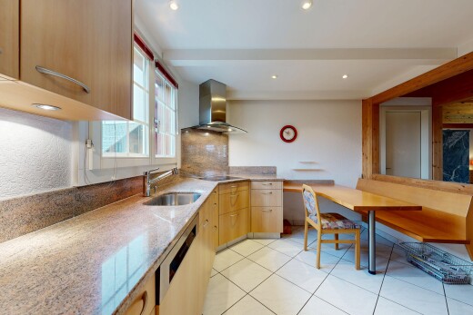 cuisine avec hotte, armoires marron clair, inside property, plans de travail en pierre, et lave-vaisselle