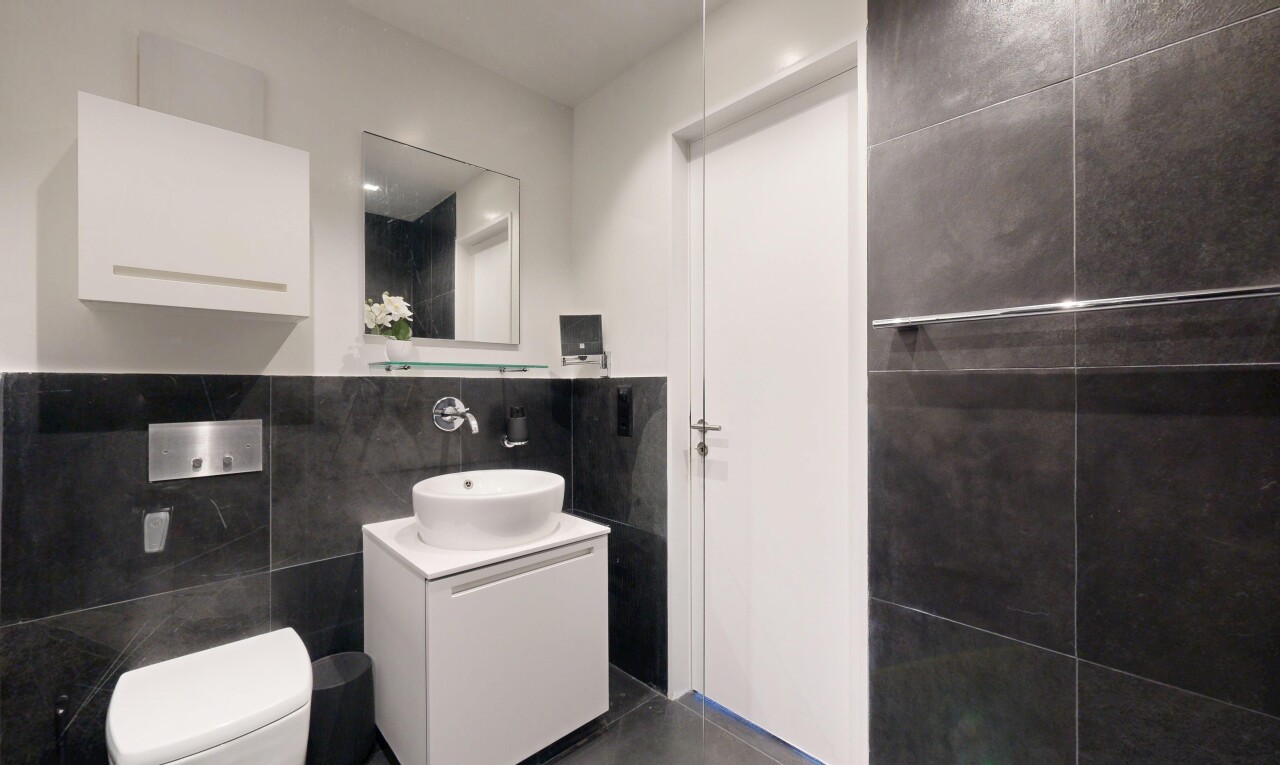 salle de bains avec mur en carrelage, tile wall, lavabo (ou coiffeuse selon le contexte), évier, et miroir
