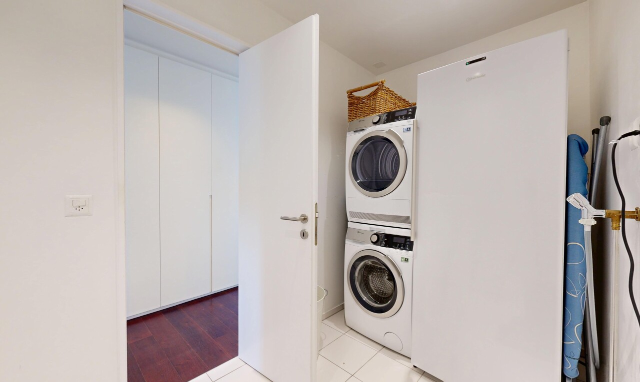 buanderie avec buanderie, light floor, inside property, lave-linge et sèche-linge superposés, et tile floor