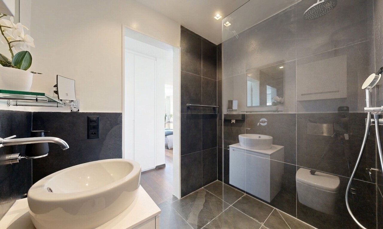 salle de bains avec lavabo (ou coiffeuse selon le contexte), salle de bain complète, miroir, évier, et douche