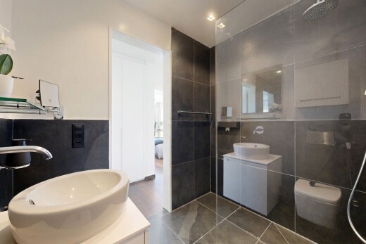 salle de bains avec lavabo (ou coiffeuse selon le contexte), salle de bain complète, miroir, évier, et douche