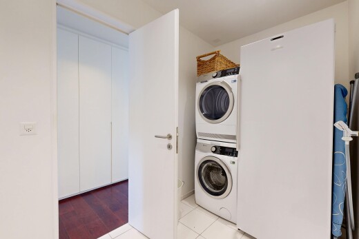 buanderie avec buanderie, light floor, inside property, lave-linge et sèche-linge superposés, et tile floor