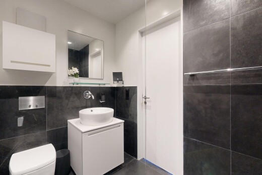 salle de bains avec mur en carrelage, tile wall, lavabo (ou coiffeuse selon le contexte), évier, et miroir