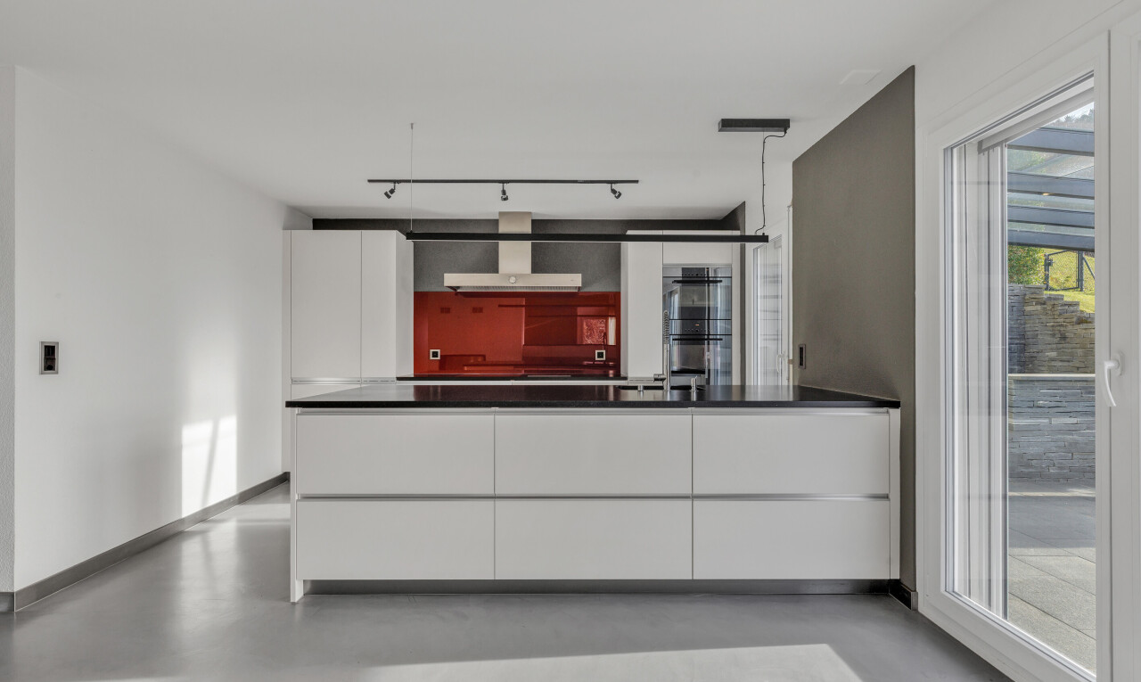 cuisine avec péninsule de cuisine, armoires à panneau plat, drywall, cloison sèche, et finished concrete floor