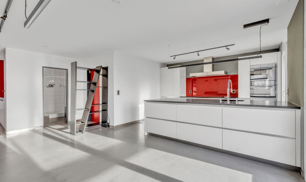 kitchen with modern cabinets, finished concrete flooring, a peninsula, double oven, and ventilation hood